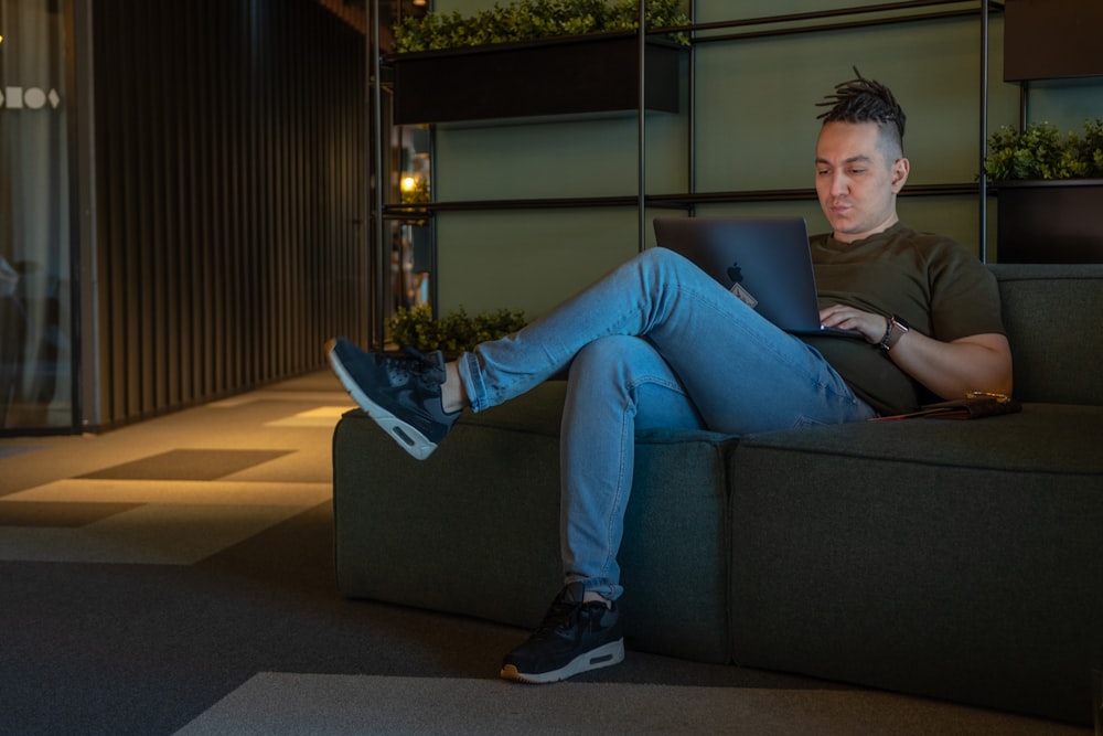 woman in gray long sleeve shirt and blue denim jeans sitting on gray couch