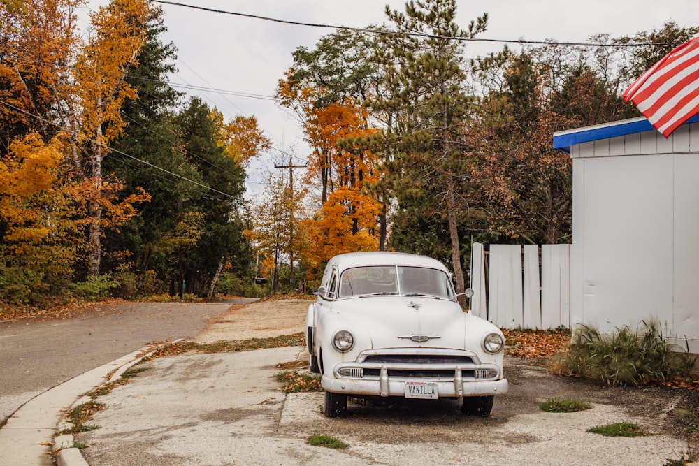 Volkswagen Beetle blanco aparcado junto a una valla de madera blanca durante el día