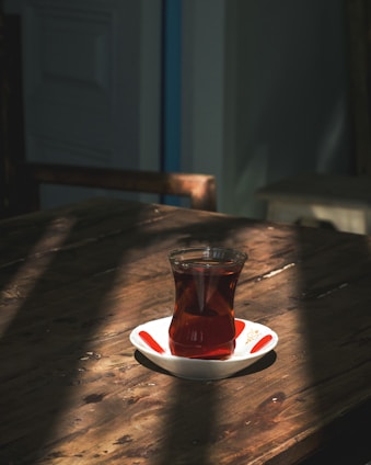 A steaming cup of strong chai placed on a rustic wooden table with morning sunlight.
