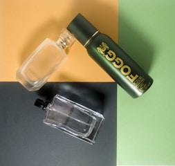 A flat lay of premium fragrance bottles with gold accents on a minimalist green background.