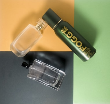A flat lay of premium fragrance bottles with gold accents on a minimalist green background.