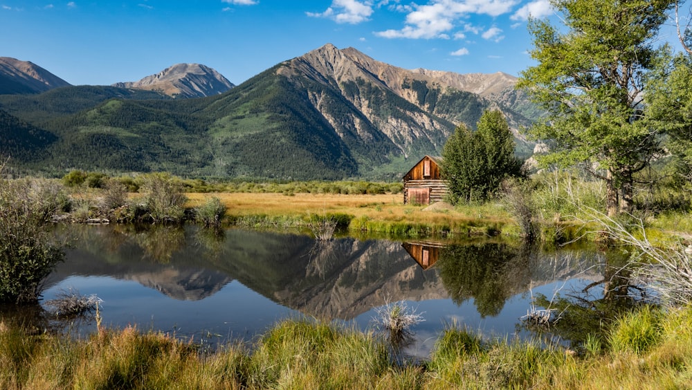 Casa di legno marrone vicino al lago e alle montagne durante il giorno