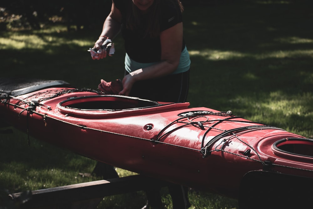 man in black t-shirt and blue denim shorts holding red kayak