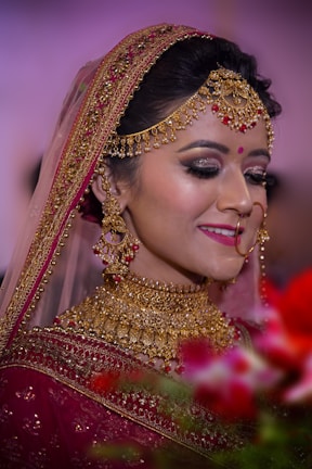 Side profile of a bride adorned with a delicate maang tikka and softly blended eye makeup, wearing a richly embroidered saree.