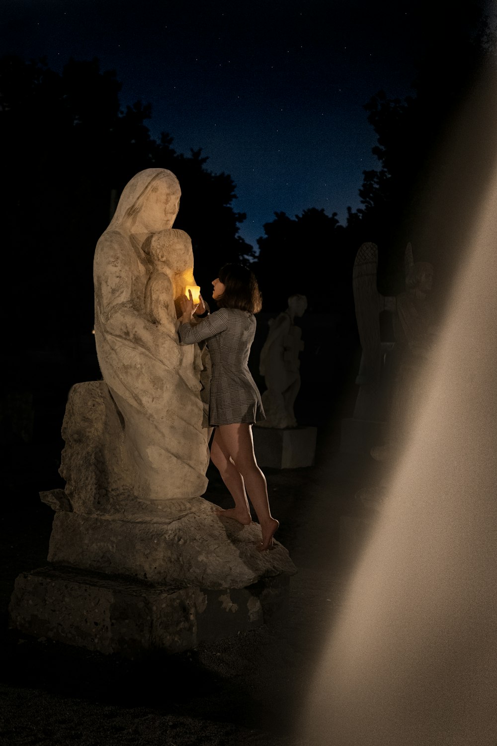 woman in black dress standing beside man in brown coat statue during night time