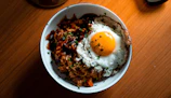 Close-up of vibrant nasi goreng topped with a perfectly fried egg and fresh herbs.