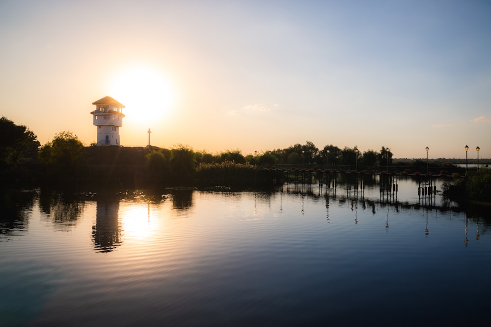 silhouette of building near body of water during sunset