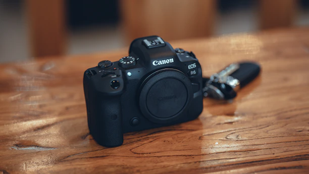 A sleek Canon EOS R6 Mark II camera resting on a wooden table with soft natural light.