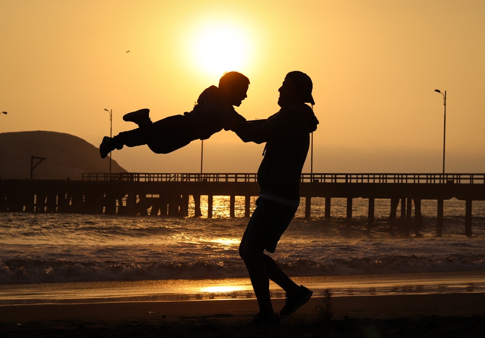 silhouette of man and woman kissing on beach during sunset