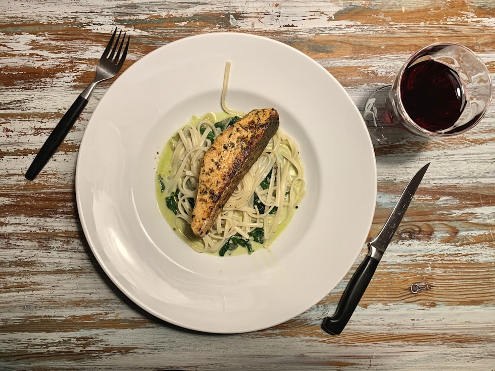 a white plate topped with pasta and chicken