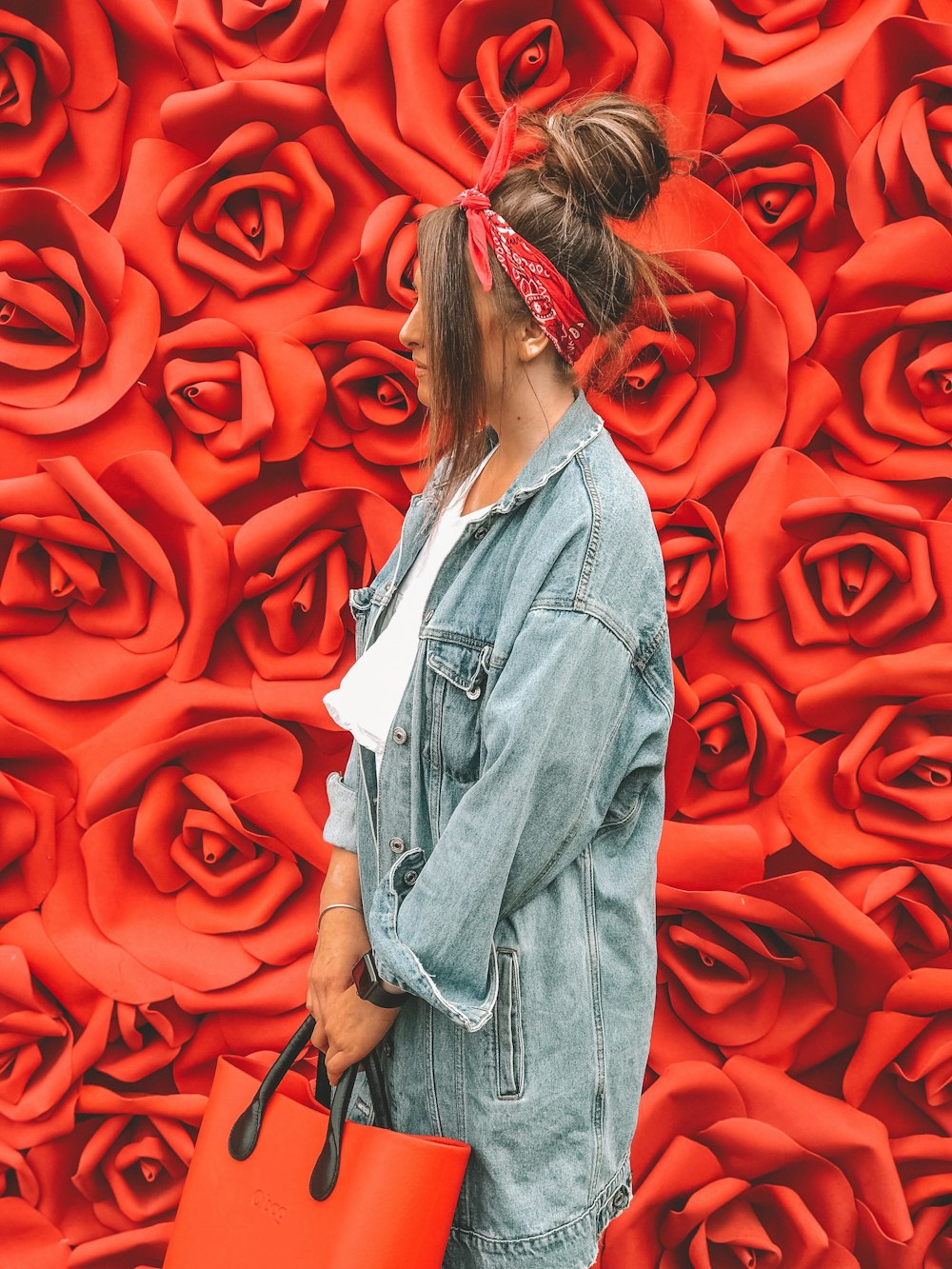 woman in blue denim jacket standing in front of red wall