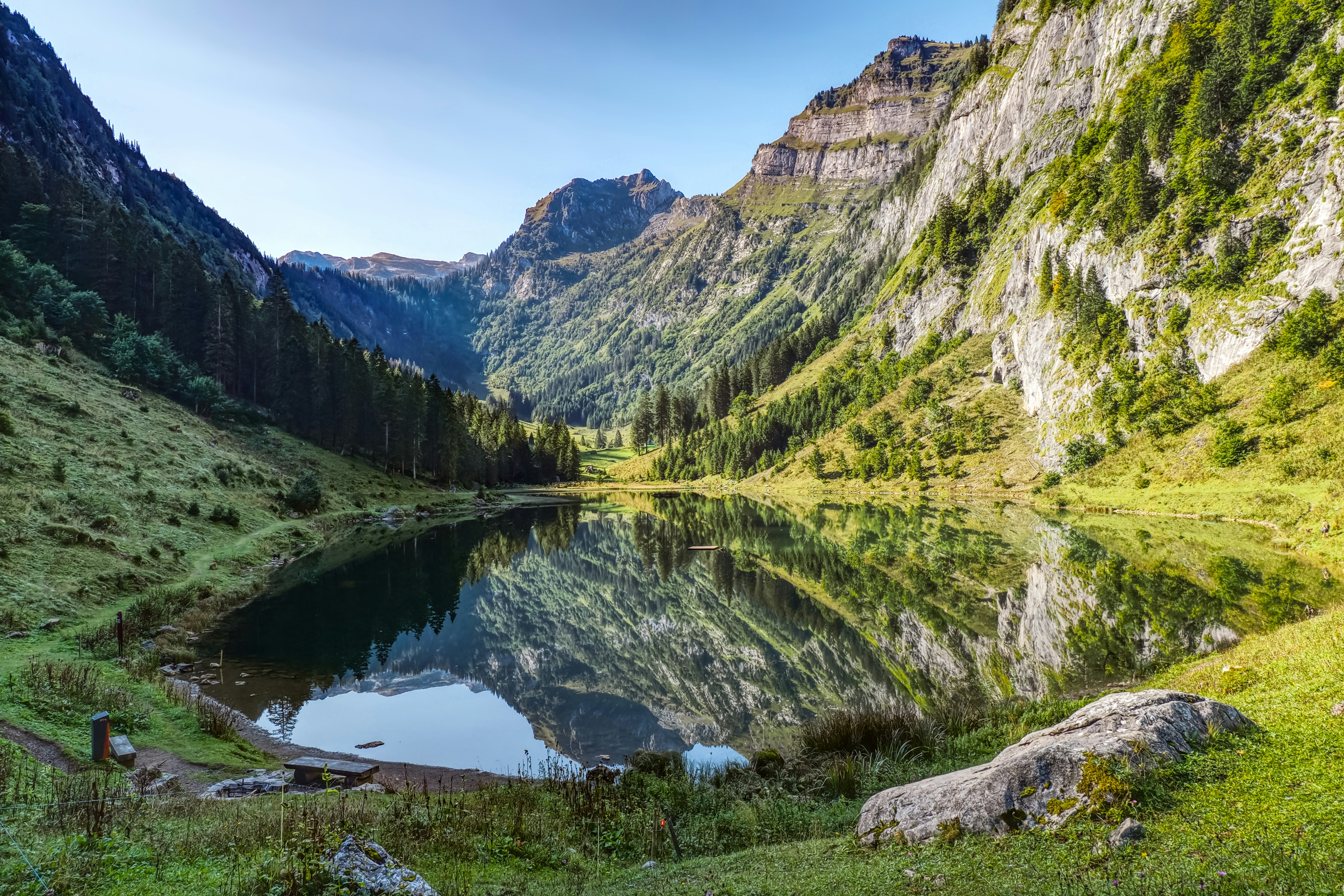 green and brown mountains beside lake under blue sky during daytime