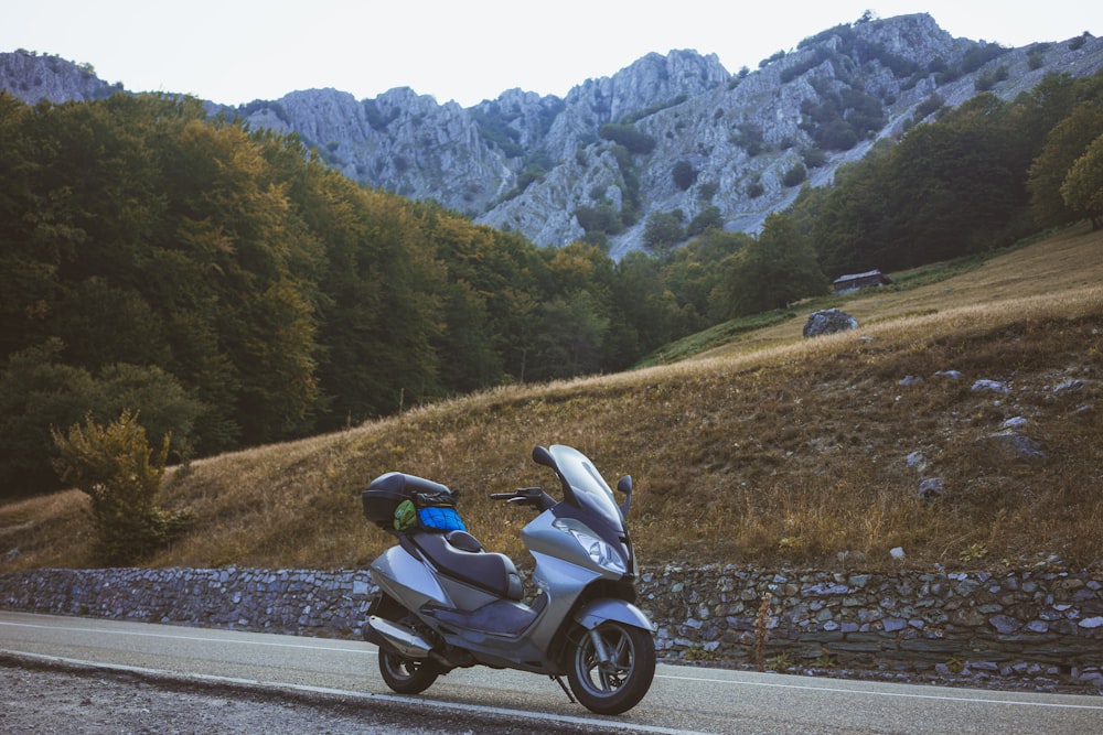 white and black sports bike on road near green trees and mountain during daytime