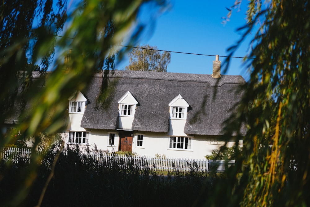 white and gray house near green trees under blue sky during daytime