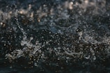 Water droplets splash and dance in motion, creating chaotic yet beautiful patterns against a dark backdrop.