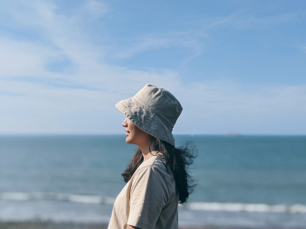 woman in gray hoodie standing near body of water during daytime