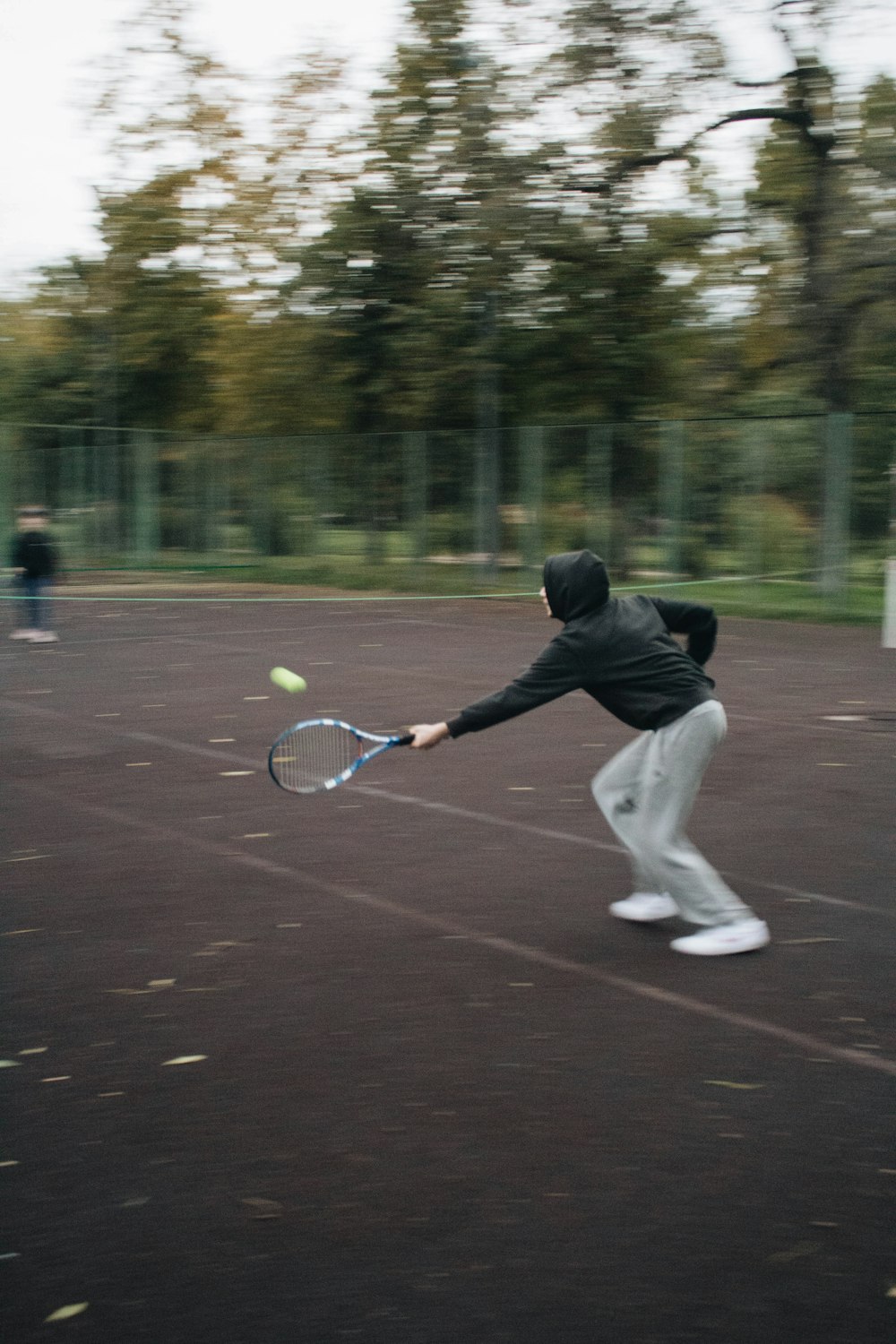 man in black jacket playing tennis during daytime