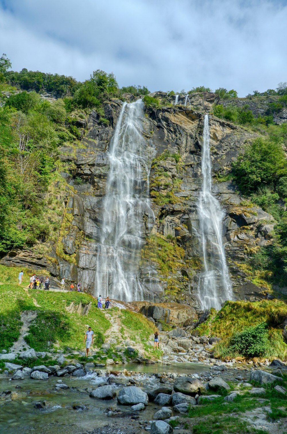 people standing on rock near waterfalls during daytime