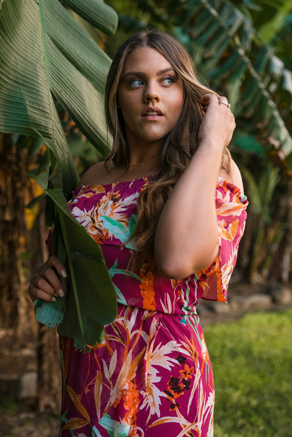 woman in pink and yellow floral dress holding her hair