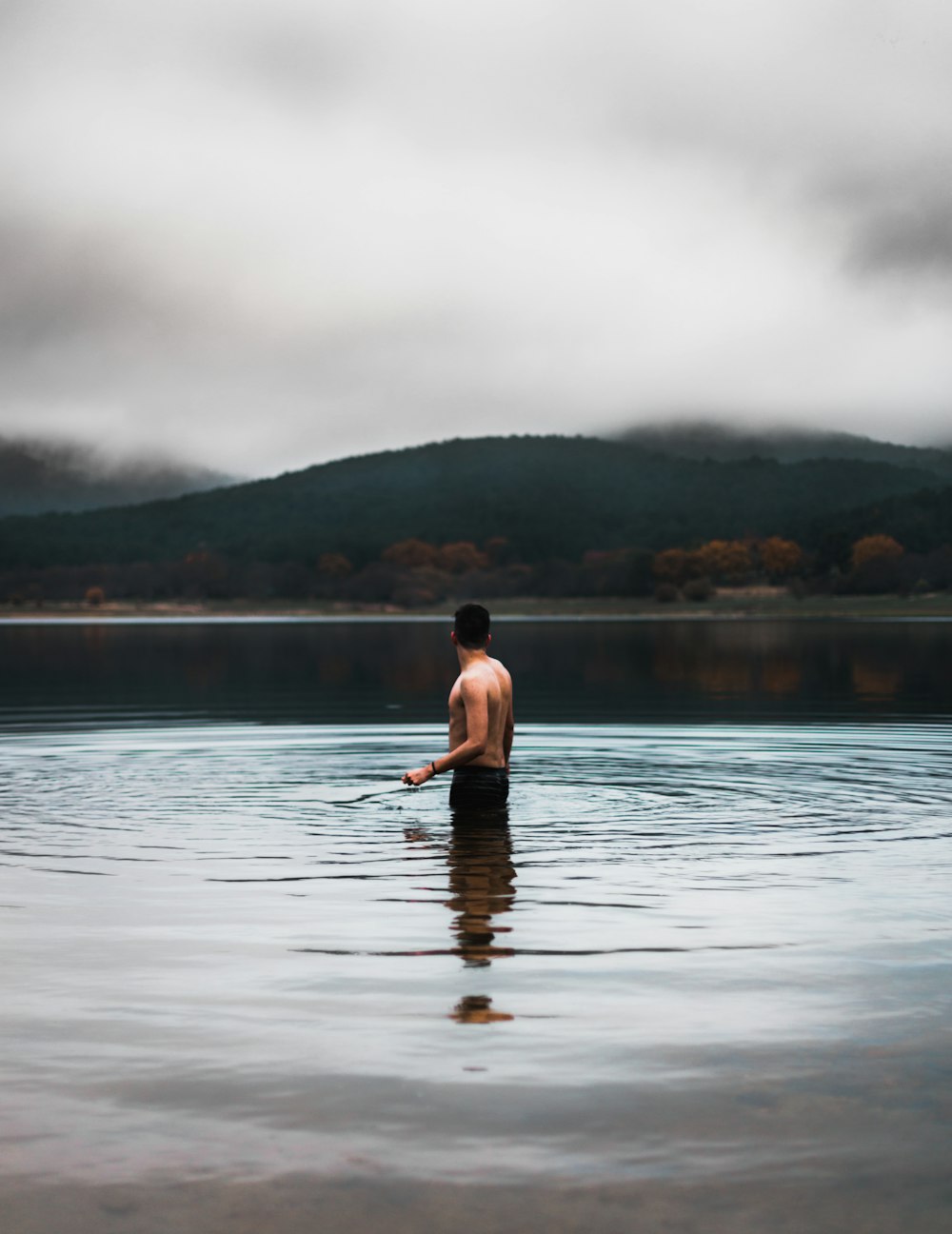 man in white shirt and black shorts standing on body of water during daytime