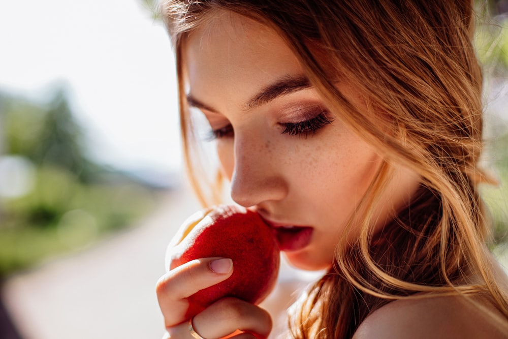woman eating red apple during daytime