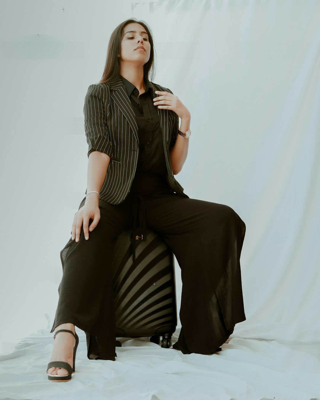 woman in black and white stripe shirt and black pants sitting on white bed