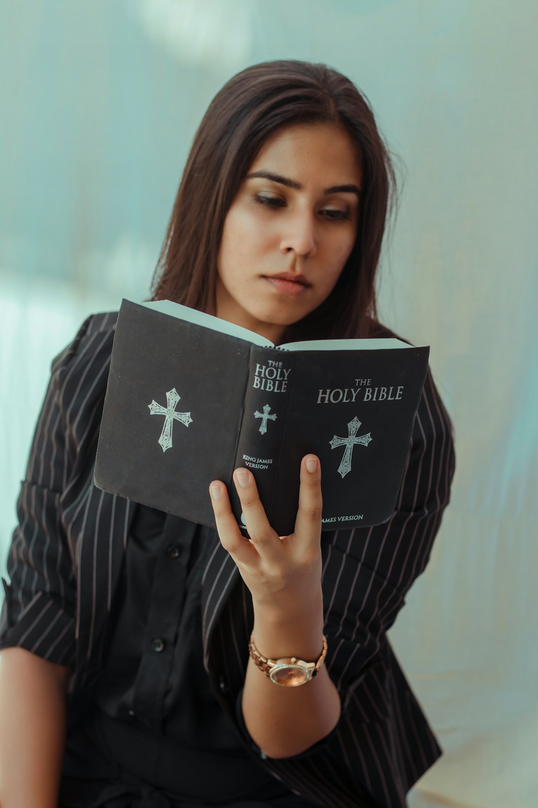 woman in blue and white striped long sleeve shirt holding black book