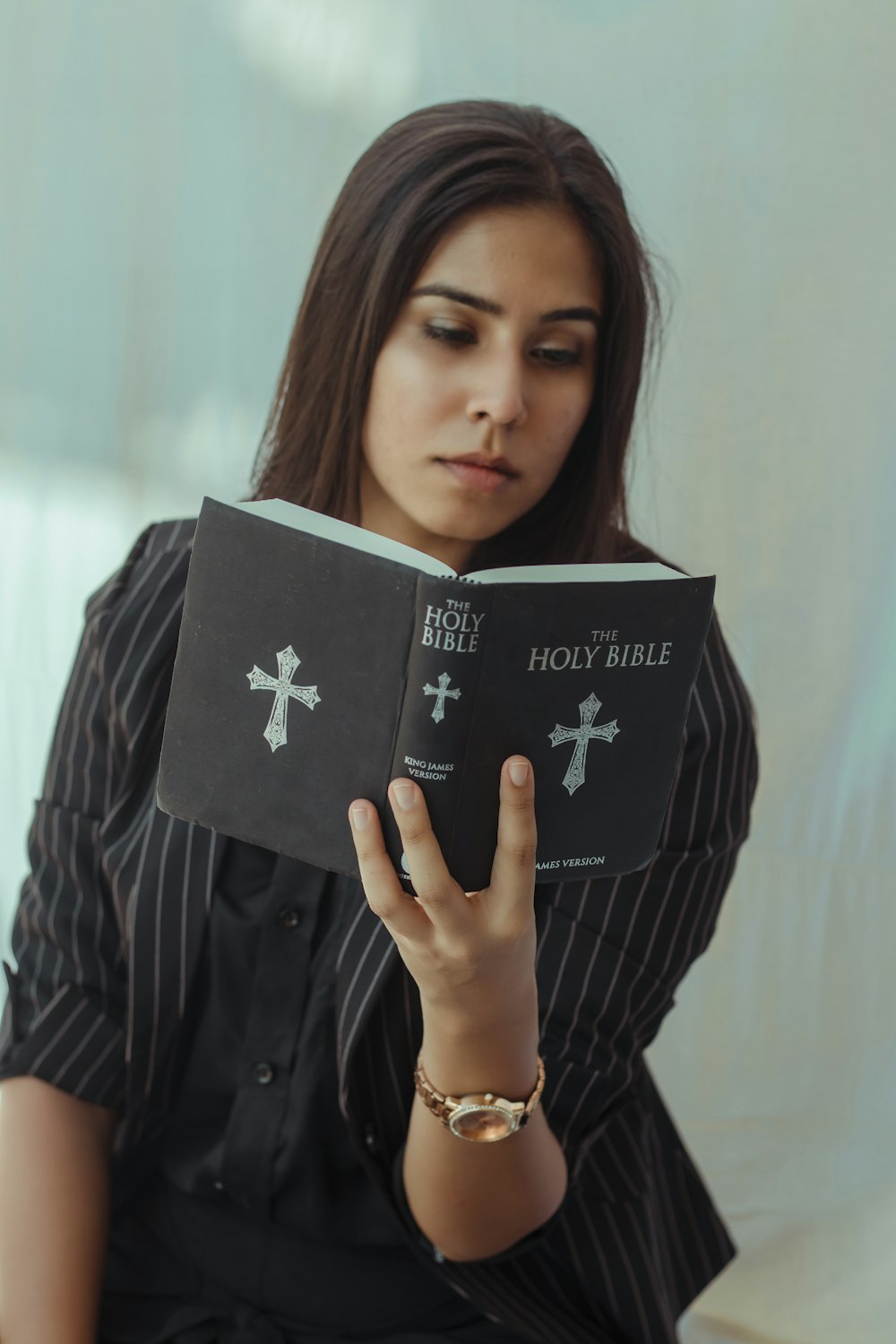 woman in blue and white striped long sleeve shirt holding black book