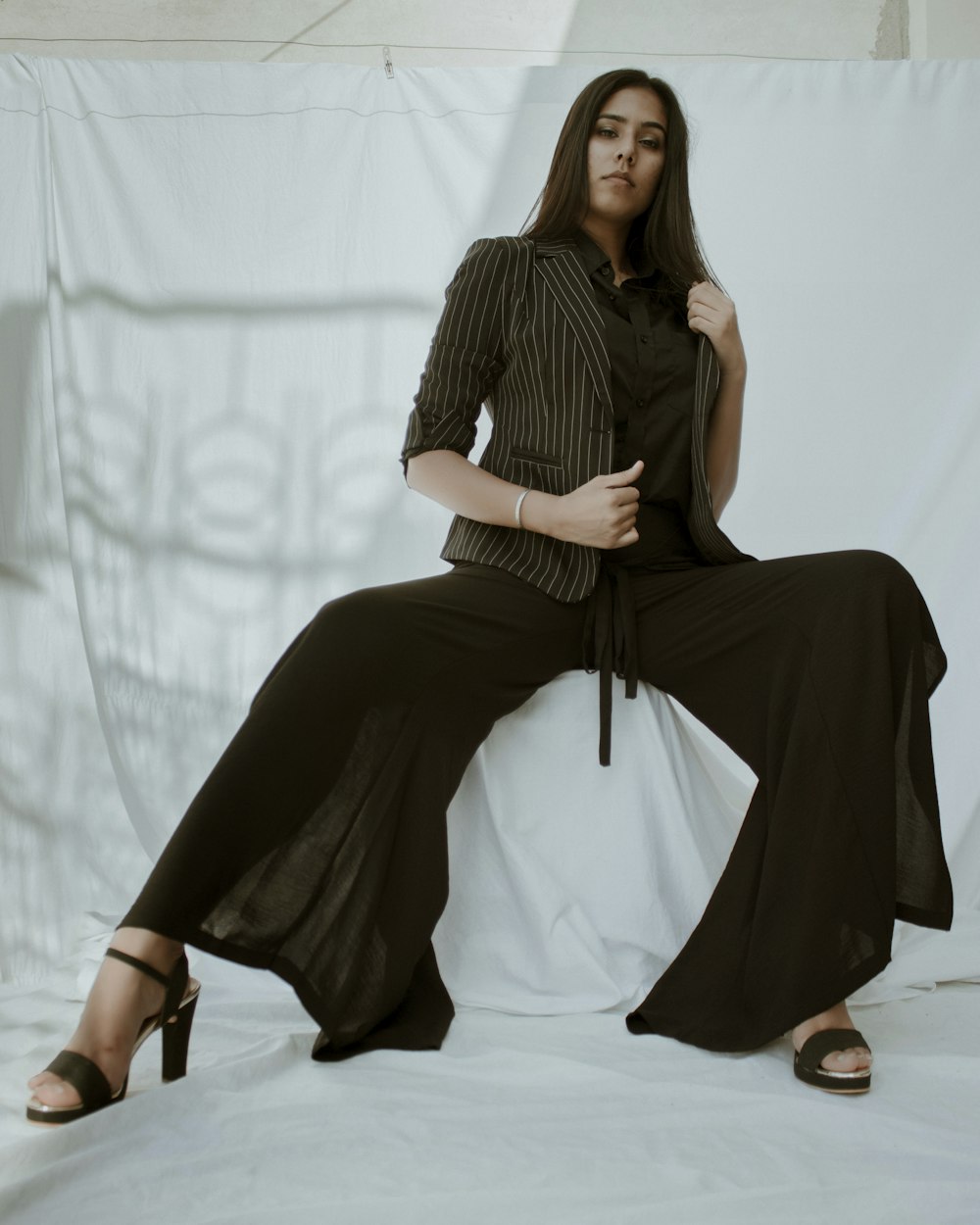 woman in black long sleeve dress sitting on white textile