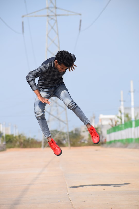 man in black and gray camouflage jacket and blue denim jeans jumping on brown field during in Kota India