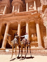 man riding horse in front of brown concrete building during daytime