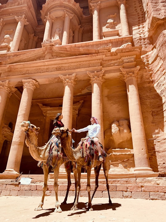 man riding horse in front of brown concrete building during daytime in Petra Jordan