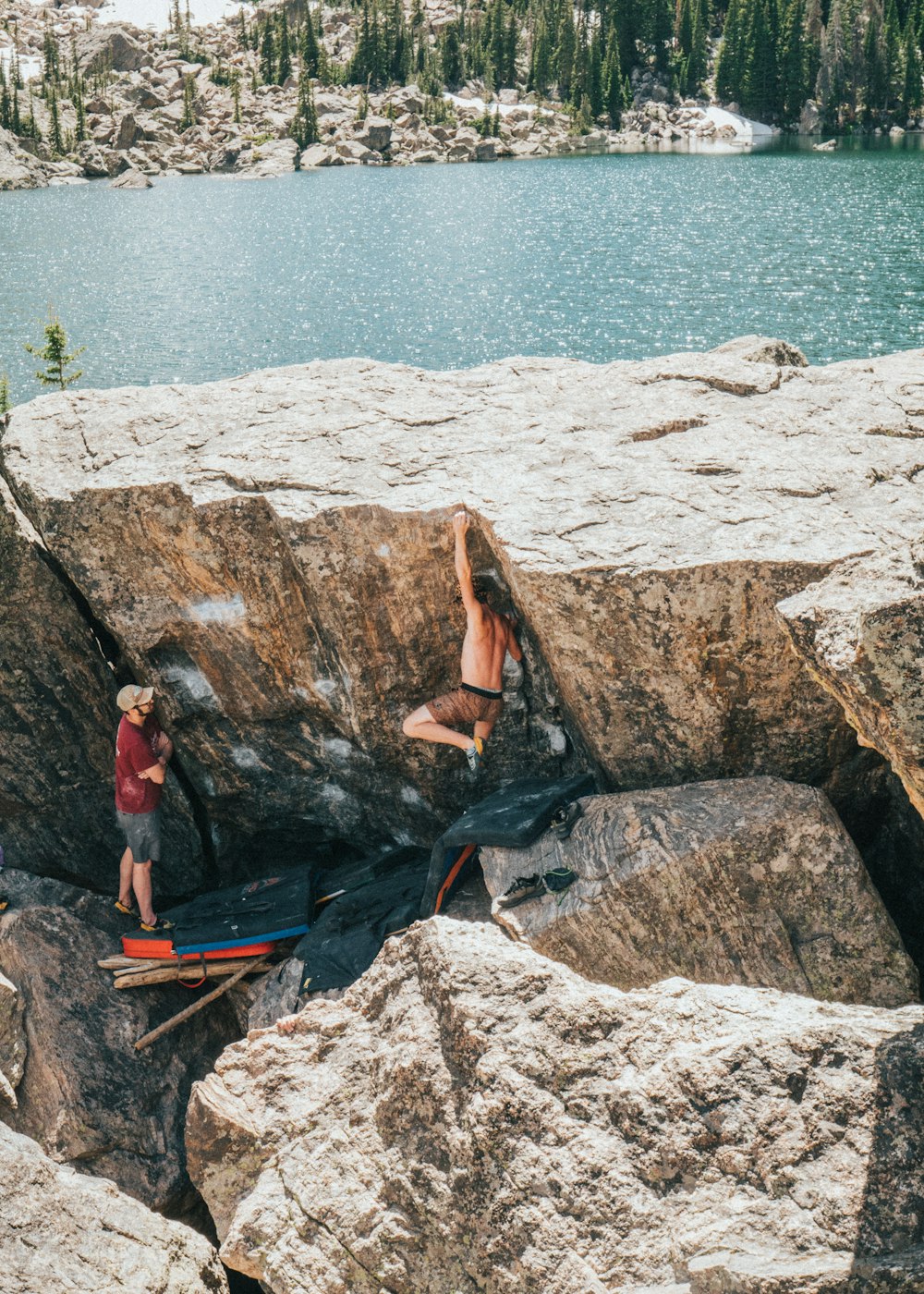 woman in red shirt sitting on rock near body of water during daytime