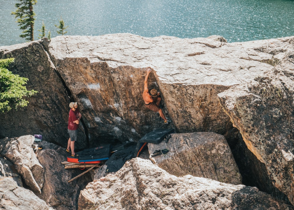 woman in red long sleeve shirt sitting on rock near body of water during daytime