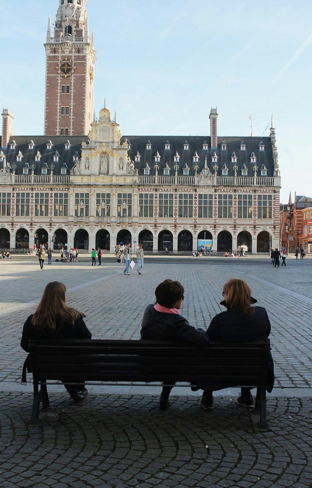 people sitting on bench in front of beige concrete building during daytime