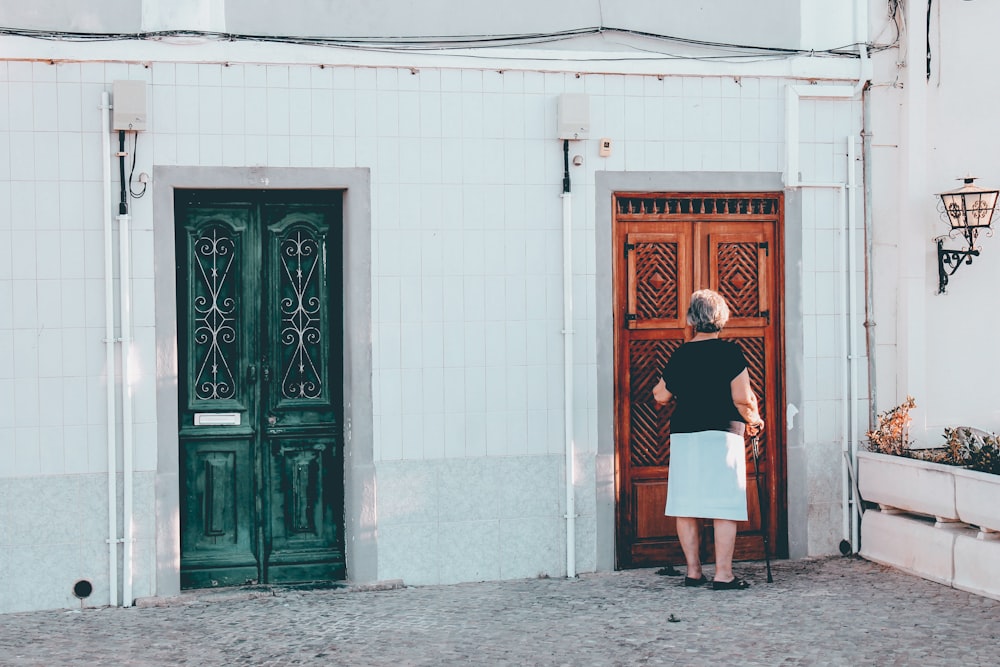 woman in black and white dress standing in front of brown wooden door