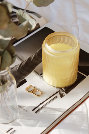 A cozy scene showing a set of hand-poured candles glowing softly beside a pair of elegant earrings.