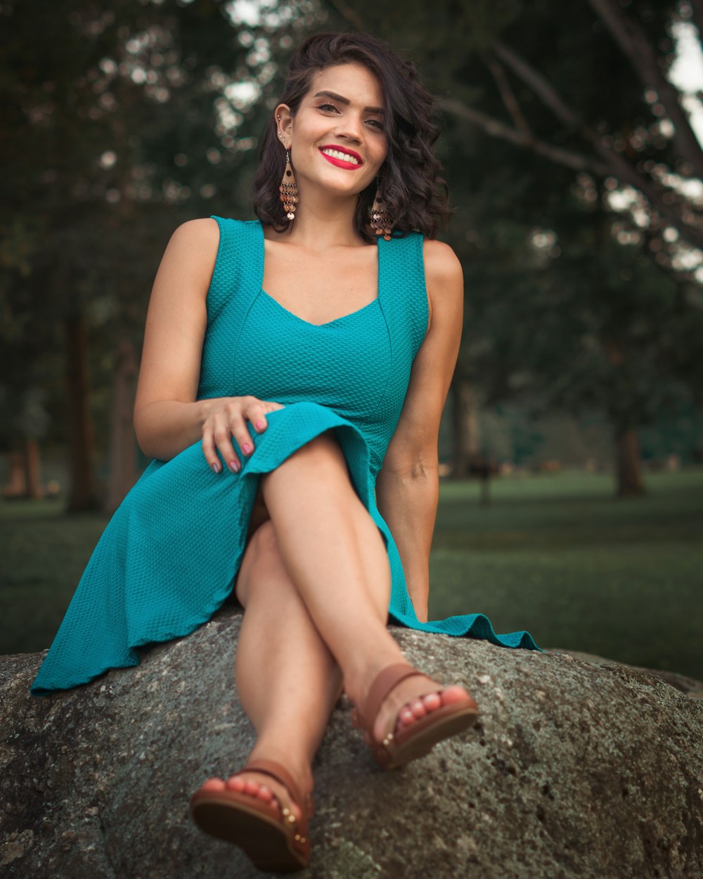 woman in blue tank dress sitting on gray rock