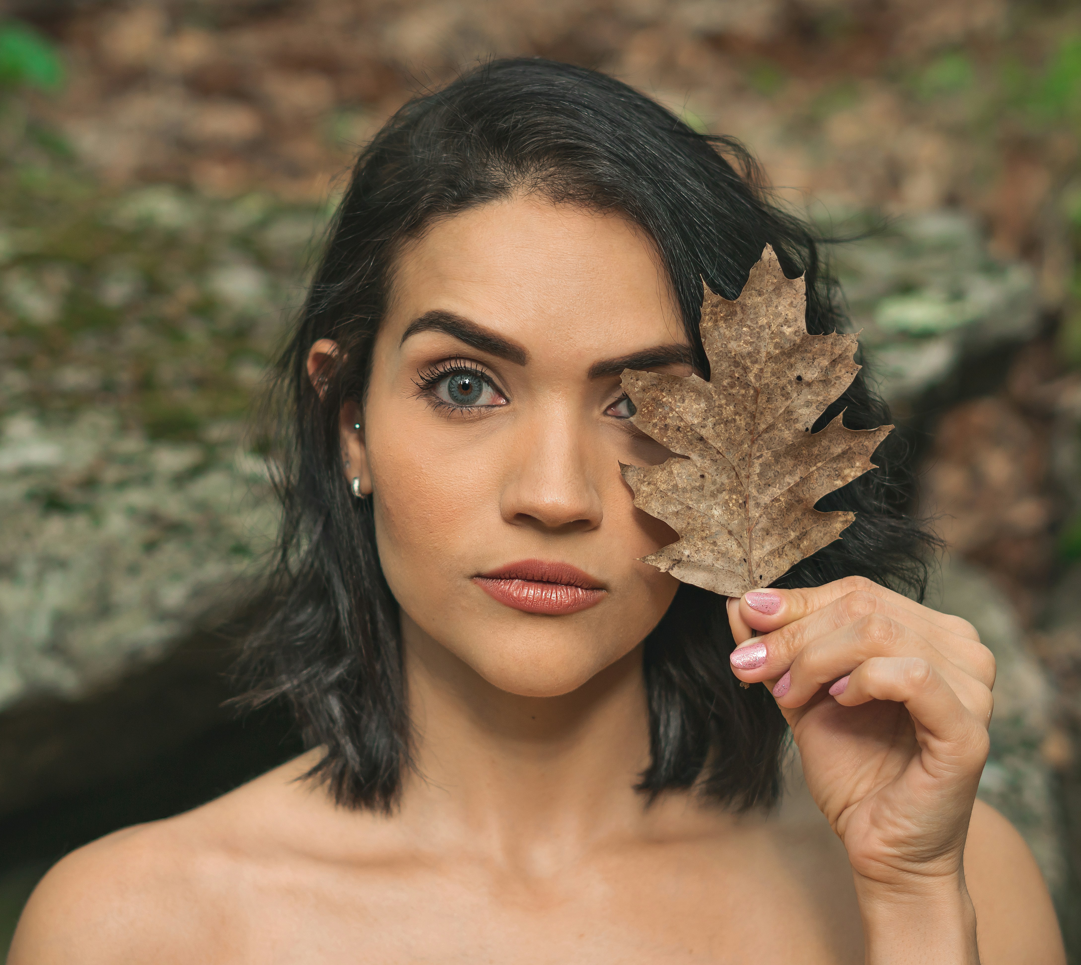 woman holding brown leaf covering her face