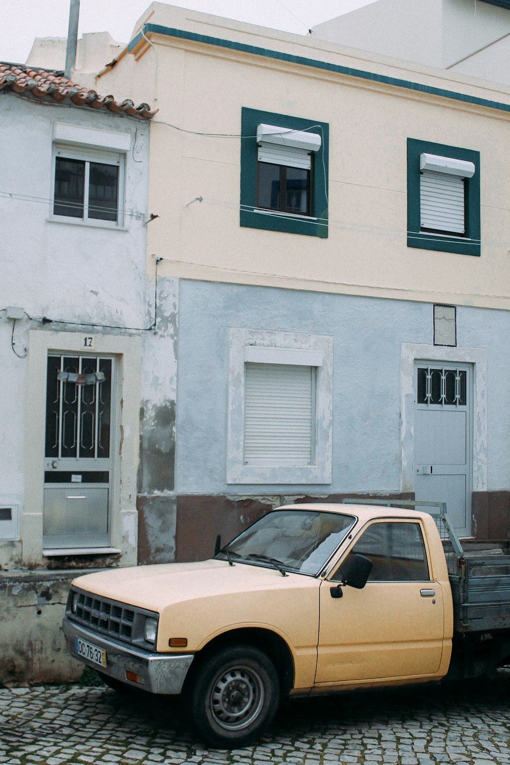 yellow car parked beside white concrete building during daytime