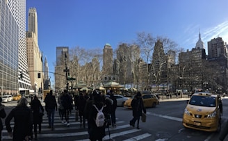 A vibrant street scene in New York City with diverse people walking and yellow taxis passing by.