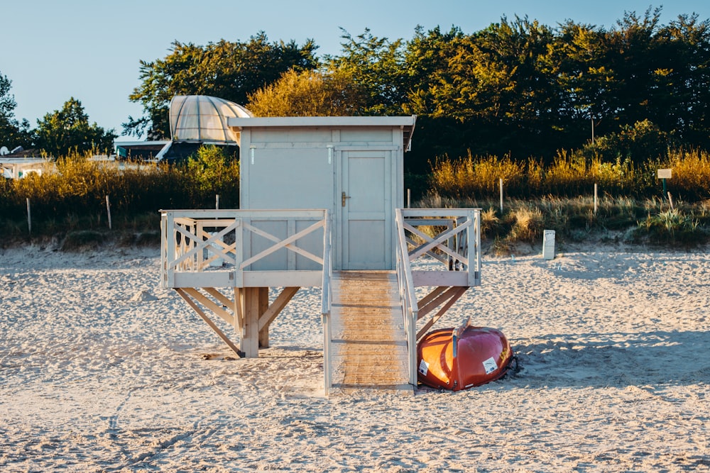 hangar en bois blanc et brun sur du sable blanc près d’un champ d’herbe verte pendant la journée