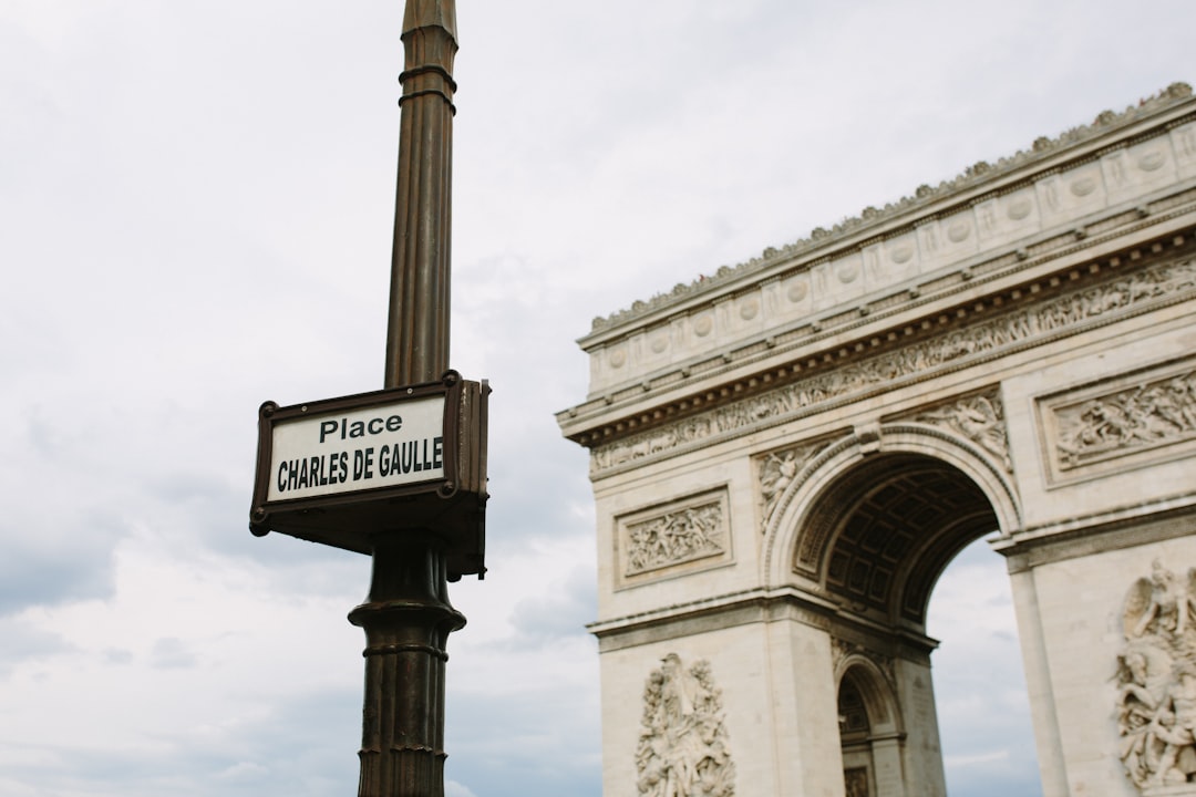 a street sign in front of an arch of triumph,