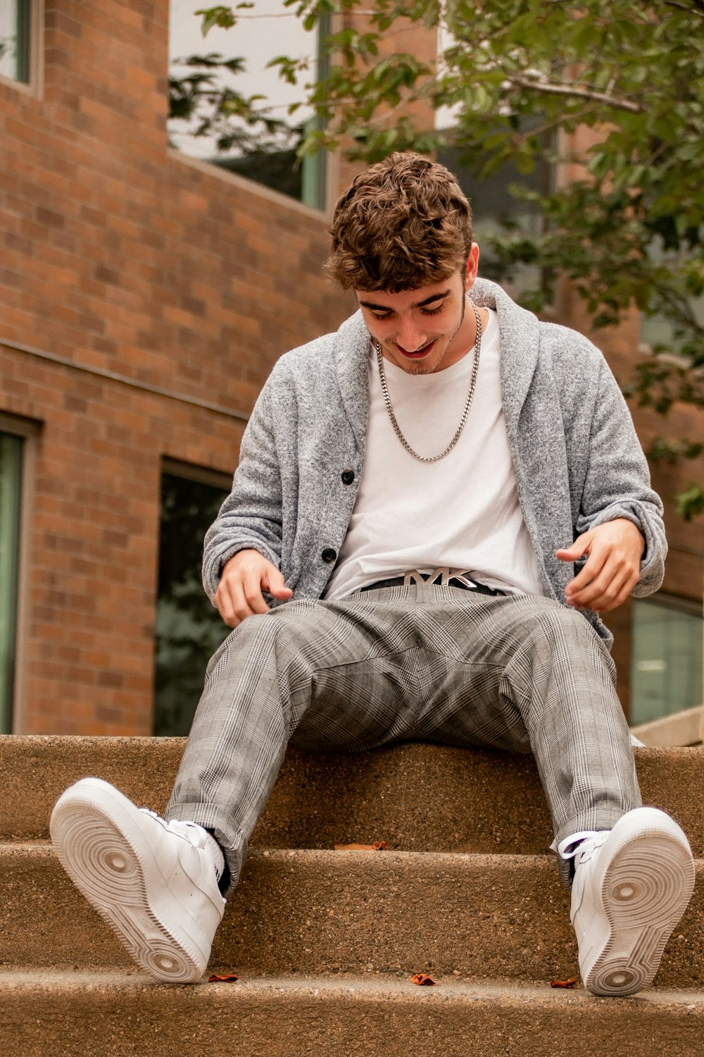 man in gray sweater and gray pants sitting on brown concrete bench during daytime