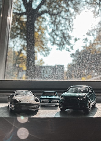 Eco-friendly toy cars lined up on a natural fiber rug with sunlight filtering through.