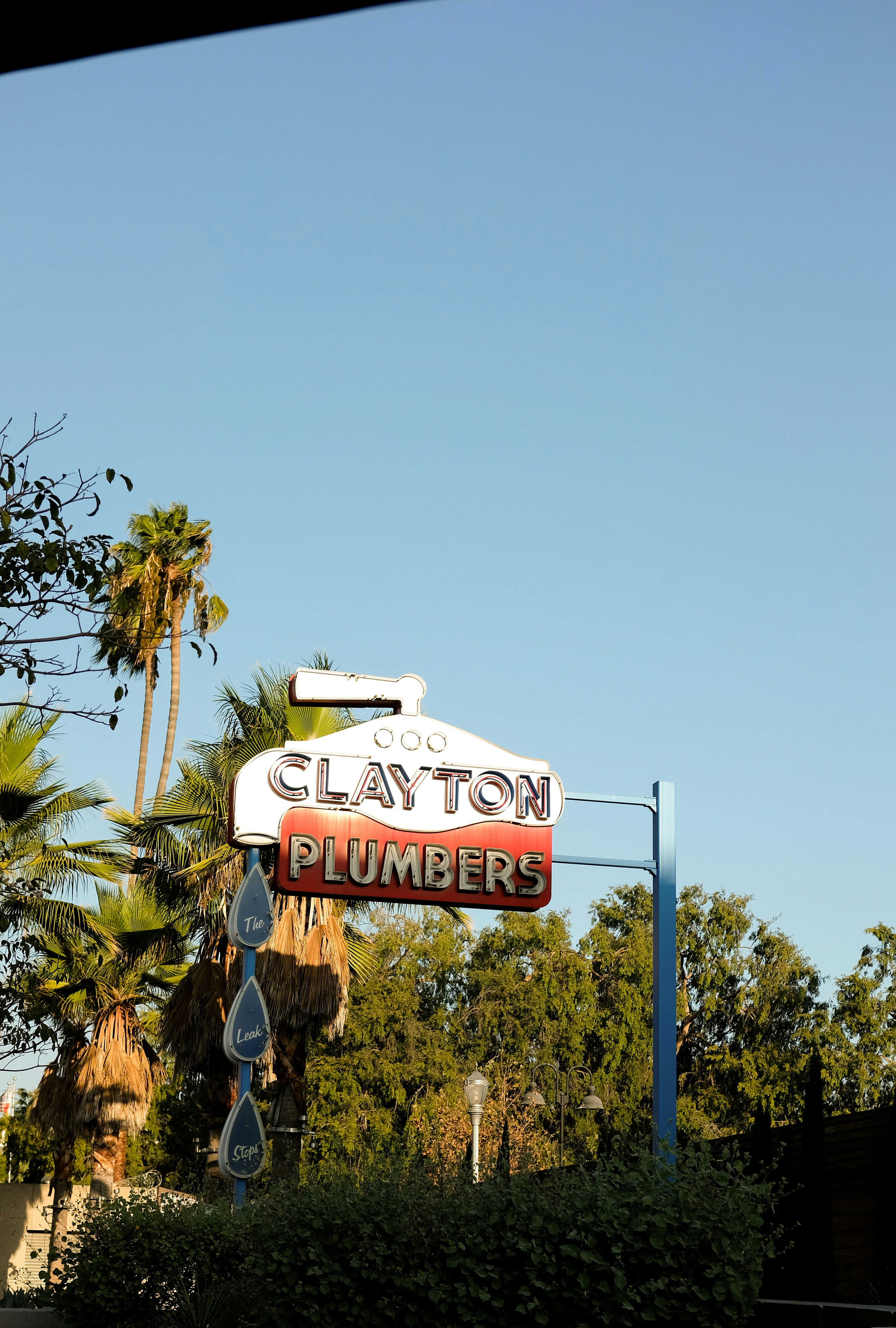 a sign for clayton plumber hangs from a pole