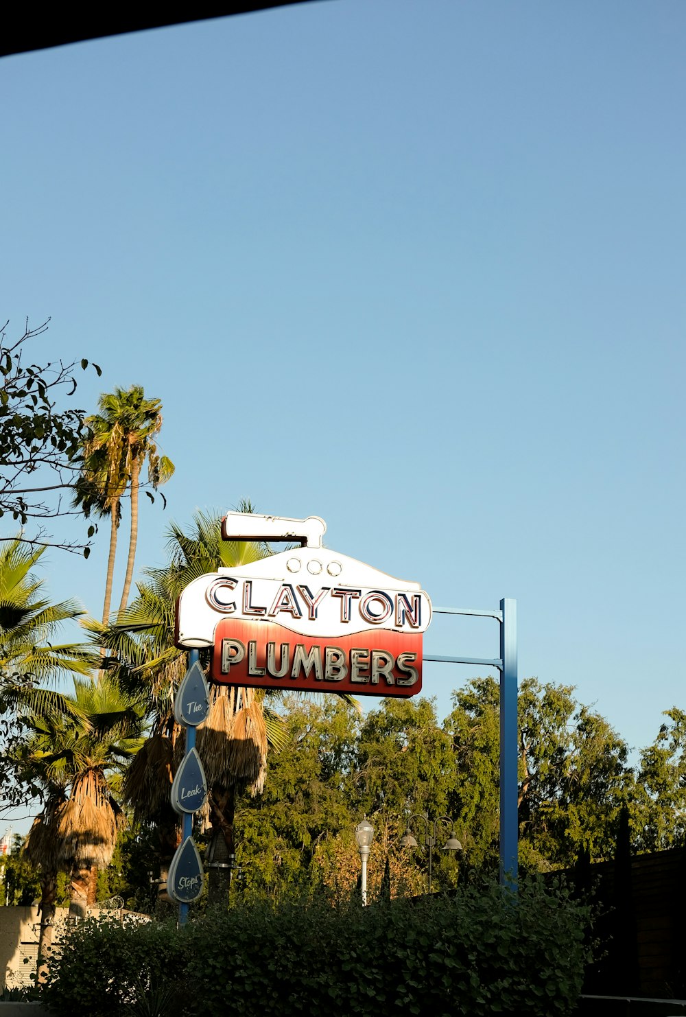 a sign for clayton plumber hangs from a pole