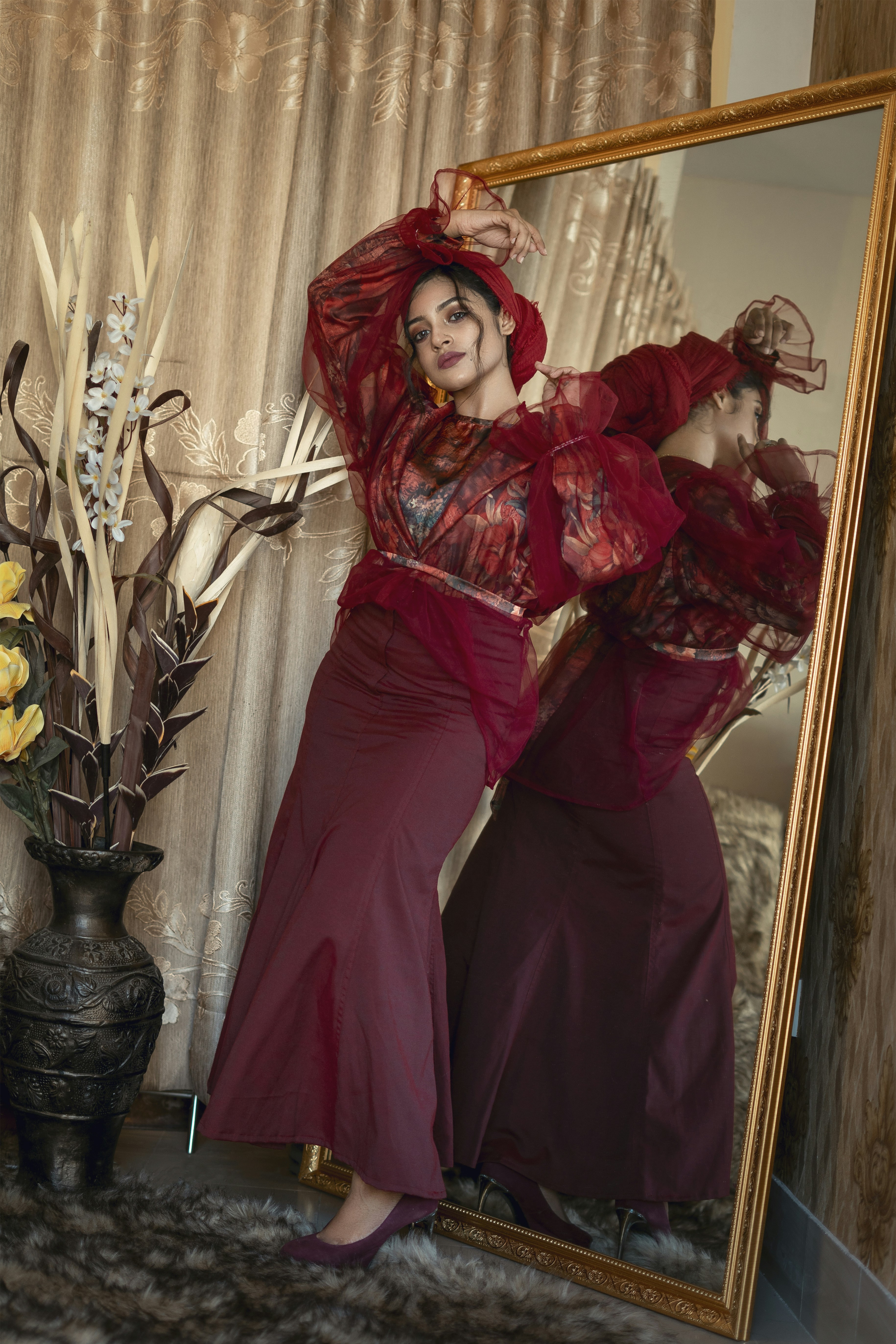 woman in red dress standing beside green plant