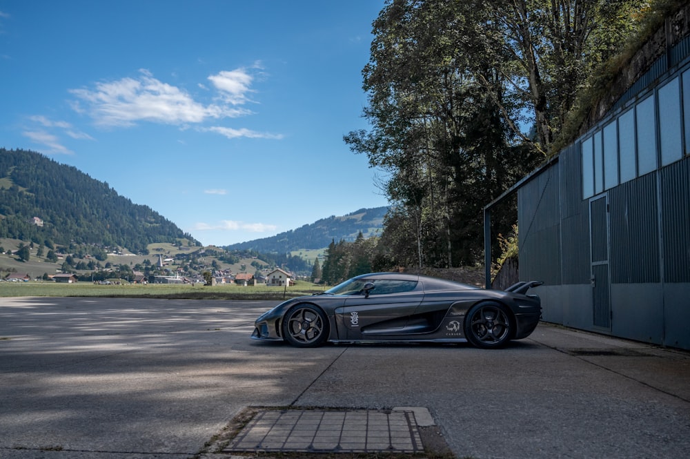 black coupe parked beside green tree during daytime