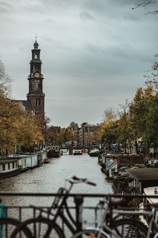 people walking on sidewalk near brown concrete tower during daytime in Westerkerk Netherlands